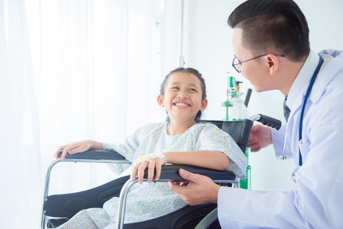 girl patient smiling with doctor while sitting on wheel chair